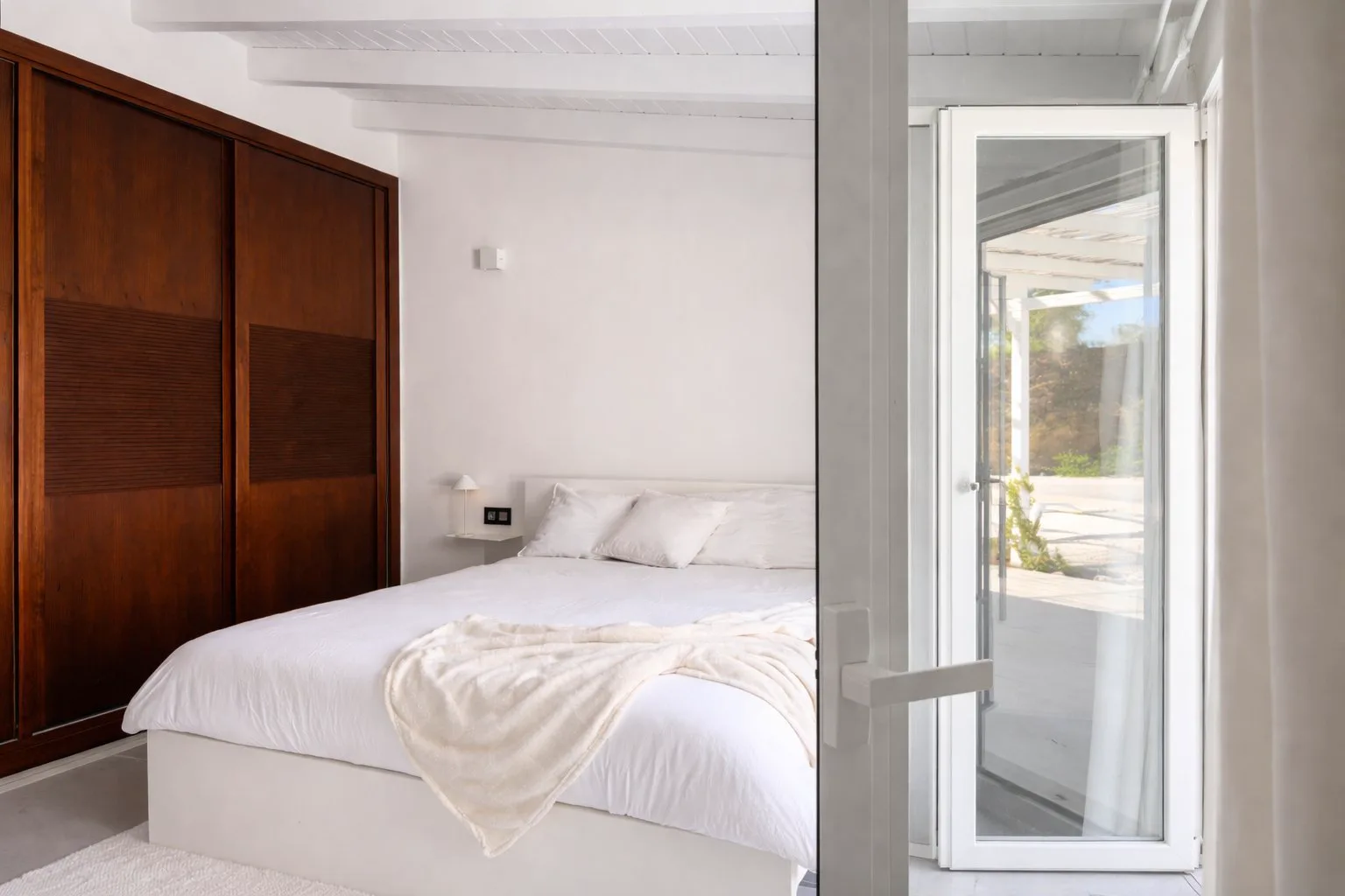 Casa Lux bedroom with terrace access, storage and warm wood details